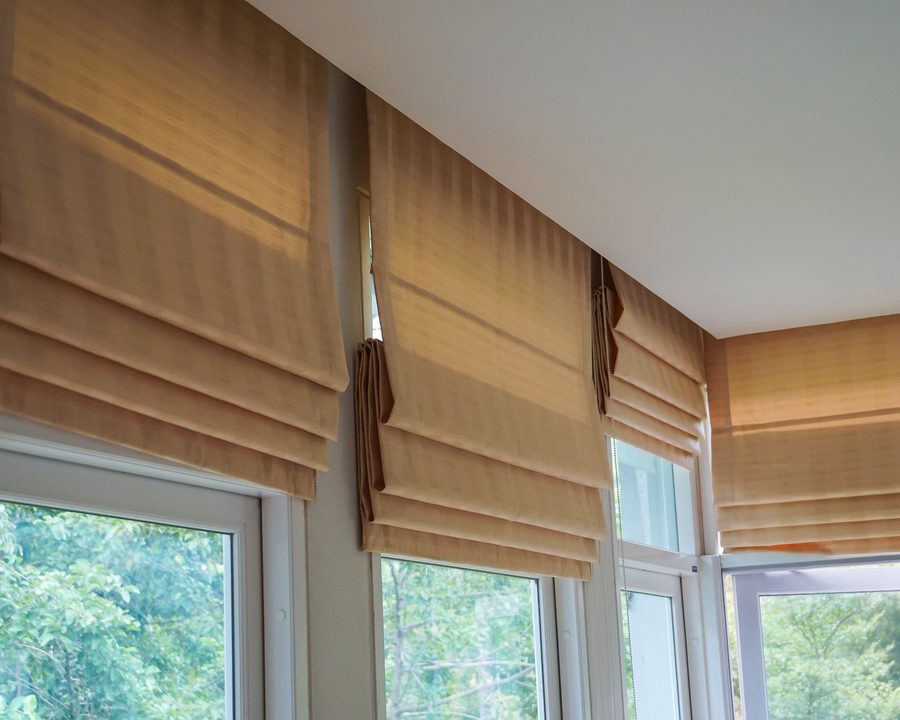 Beige roman blinds fitted across a bright garden-facing window